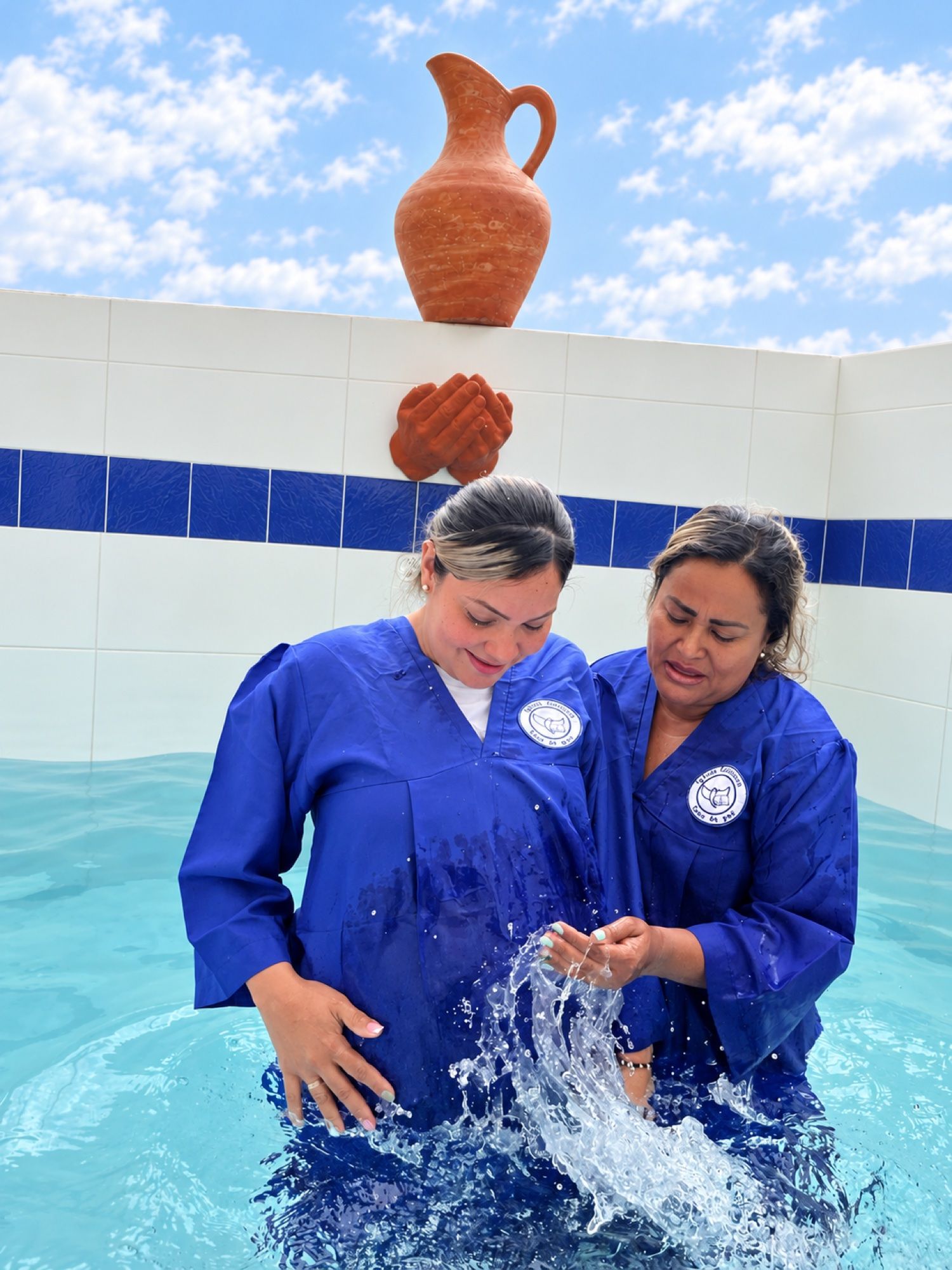 Bautizo en agua: dos mujeres con túnica azul en el estanque bautismal